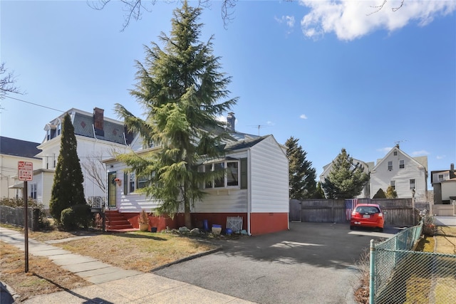 view of front of home featuring entry steps, aphalt driveway, and fence