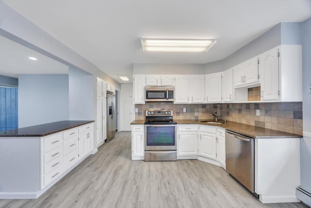 kitchen featuring white cabinets, light wood-style floors, stainless steel appliances, and a sink