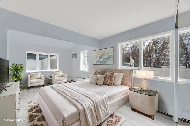 bedroom with vaulted ceiling, multiple windows, and light wood-style flooring