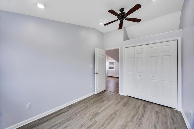 unfurnished bedroom featuring lofted ceiling, wood finished floors, a ceiling fan, baseboards, and a closet