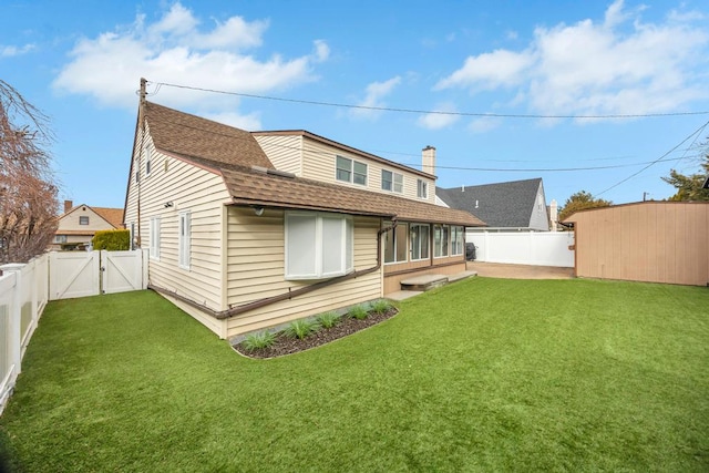 rear view of property featuring a yard, a gate, a fenced backyard, and an outdoor structure