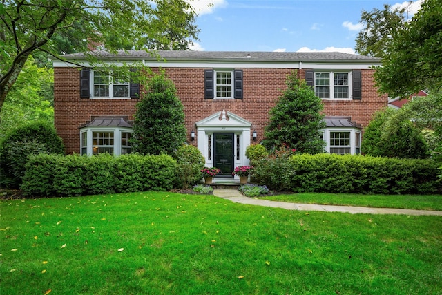 colonial-style house featuring brick siding and a front yard