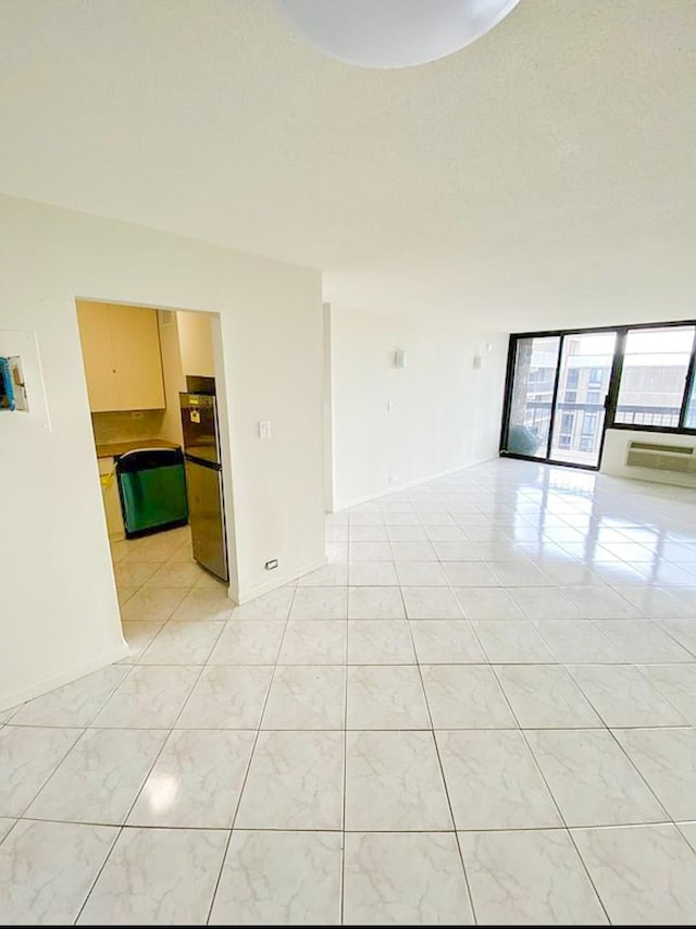 empty room featuring baseboards, floor to ceiling windows, and light tile patterned flooring