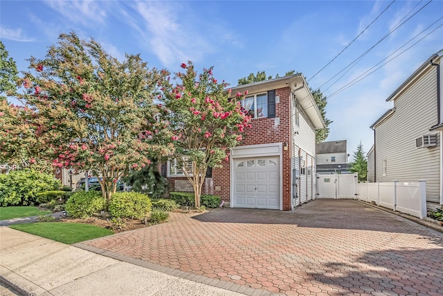 view of front of property featuring decorative driveway, brick siding, fence, and a gate