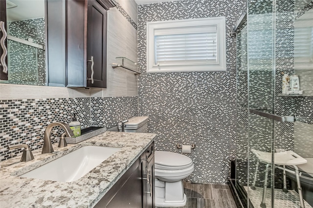 bathroom with tile walls, tasteful backsplash, toilet, a shower stall, and vanity