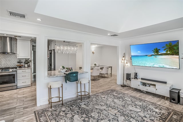 kitchen with visible vents, white cabinets, wall chimney exhaust hood, tasteful backsplash, and gas stove