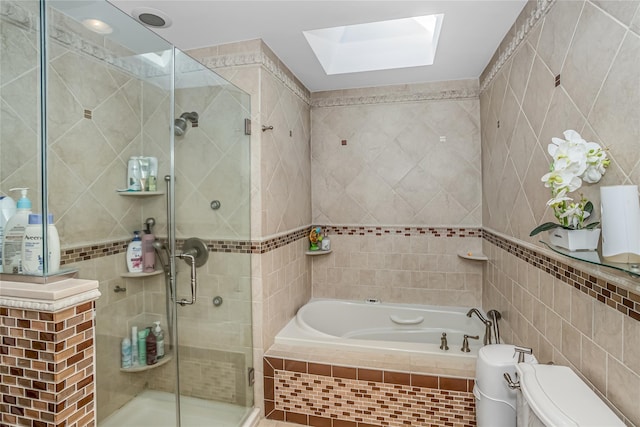 bathroom featuring a garden tub, toilet, a skylight, tile walls, and a shower stall