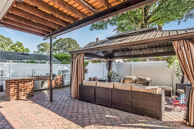 view of patio with an outdoor kitchen, a fenced backyard, grilling area, a gazebo, and outdoor lounge area