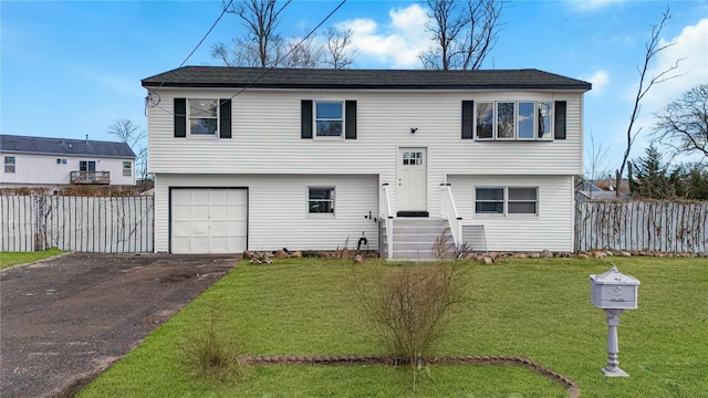 split foyer home featuring aphalt driveway, a garage, fence, and a front yard