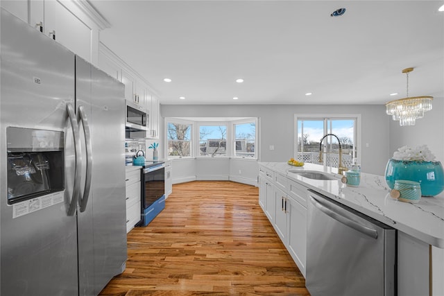 kitchen featuring appliances with stainless steel finishes, light wood-type flooring, a sink, and white cabinets