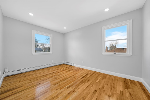 unfurnished room featuring a baseboard heating unit, recessed lighting, light wood finished floors, and baseboards