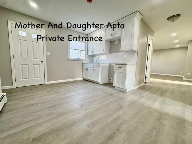 kitchen with light countertops, baseboards, white cabinetry, and light wood finished floors