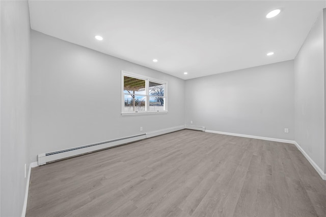 spare room featuring a baseboard radiator, baseboards, wood finished floors, and recessed lighting