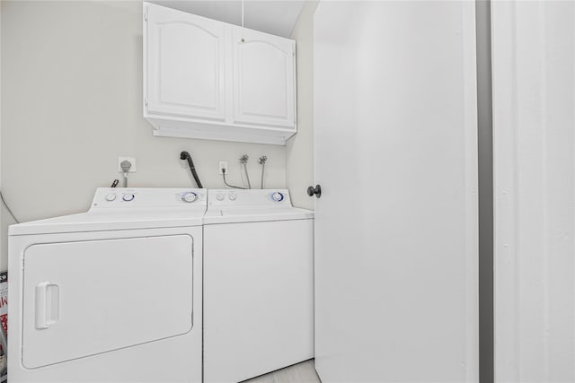 clothes washing area featuring washing machine and dryer and cabinet space