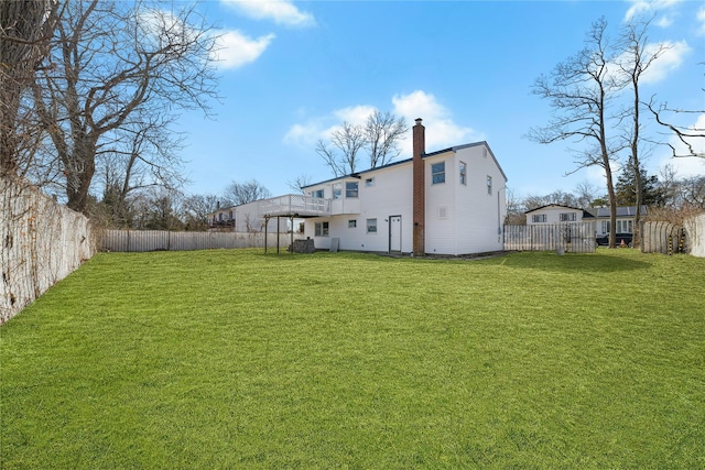 rear view of house with a fenced backyard, a chimney, and a lawn