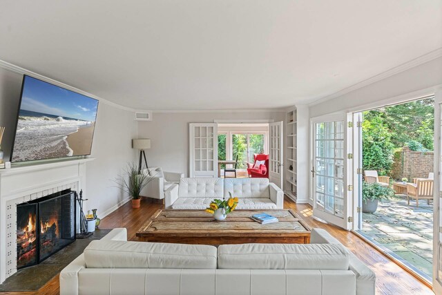 27 Notamiset Rd, Westhampton Beach, NY 11978 - living room featuring a warm lit fireplace, plenty of natural light, wood finished floors, and visible vents