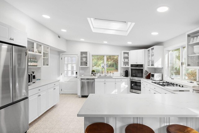27 Notamiset Rd, Westhampton Beach, NY 11978 - kitchen featuring stainless steel appliances, light floors, a skylight, and a kitchen breakfast bar