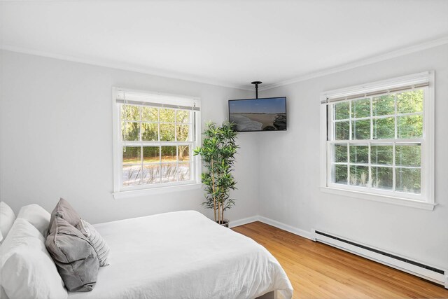 27 Notamiset Rd, Westhampton Beach, NY 11978 - bedroom featuring multiple windows, ornamental molding, baseboard heating, and wood finished floors