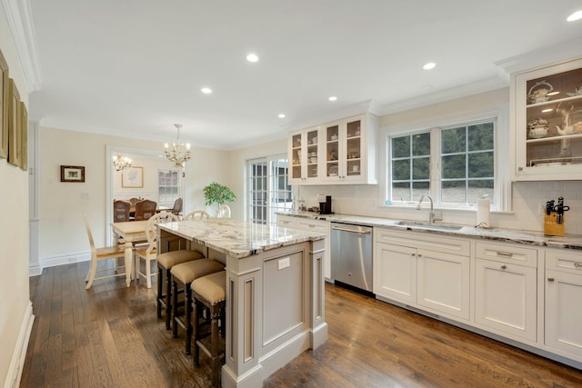 kitchen with stainless steel dishwasher, a kitchen island, a sink, and crown molding