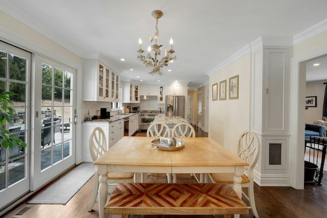 dining space with a chandelier, visible vents, crown molding, and wood finished floors