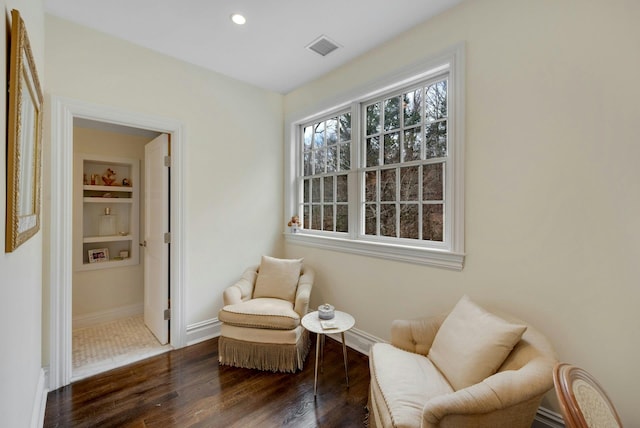 living area featuring built in features, visible vents, baseboards, and wood finished floors