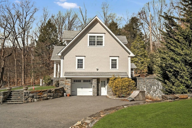 view of home's exterior featuring roof with shingles, a yard, an attached garage, stone siding, and driveway