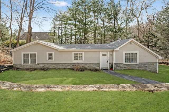 single story home with stone siding, a chimney, and a front lawn