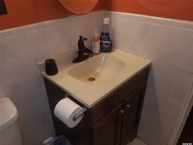 bathroom featuring tile walls, vanity, and toilet