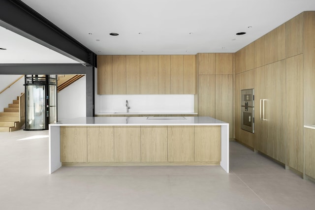 kitchen featuring finished concrete flooring, a spacious island, light brown cabinetry, a sink, and modern cabinets