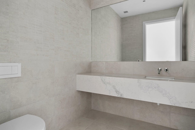 half bath featuring tile walls, visible vents, toilet, vanity, and tile patterned flooring