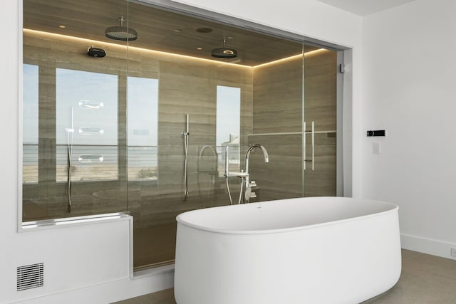 full bathroom featuring a freestanding tub, a shower stall, visible vents, and baseboards