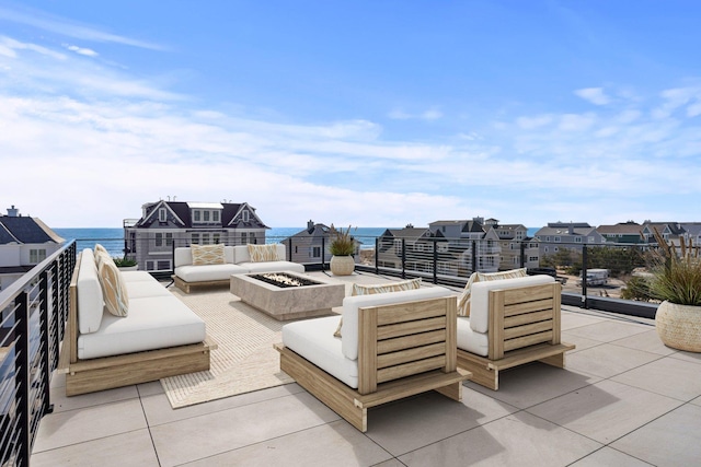 view of patio / terrace with a balcony, a water view, and an outdoor living space with a fire pit