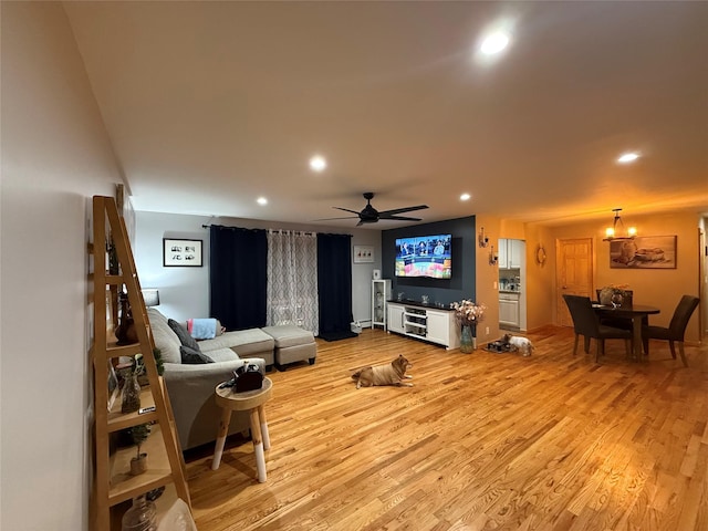 living room featuring light wood-style floors, ceiling fan with notable chandelier, and recessed lighting