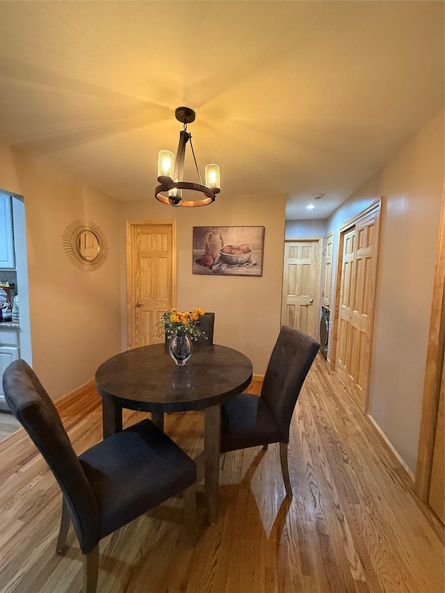 dining space featuring light wood-style floors, baseboards, and a notable chandelier