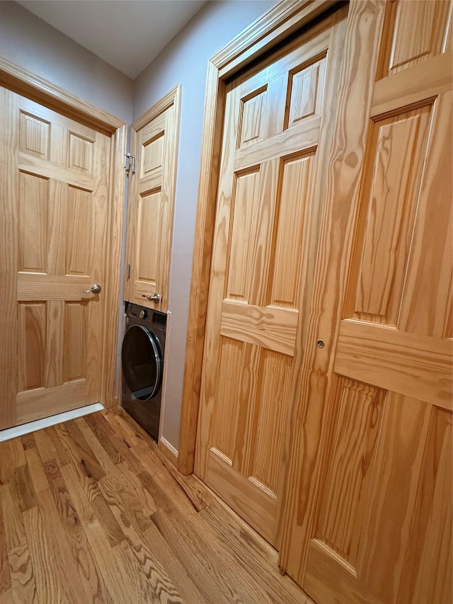 laundry area featuring light wood-type flooring, washer / dryer, and cabinet space