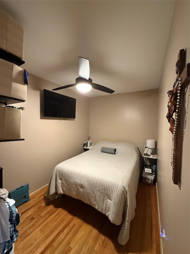 bedroom featuring a ceiling fan, baseboards, and wood finished floors