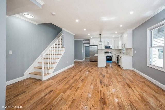 kitchen with stainless steel appliances, light countertops, white cabinets, and crown molding