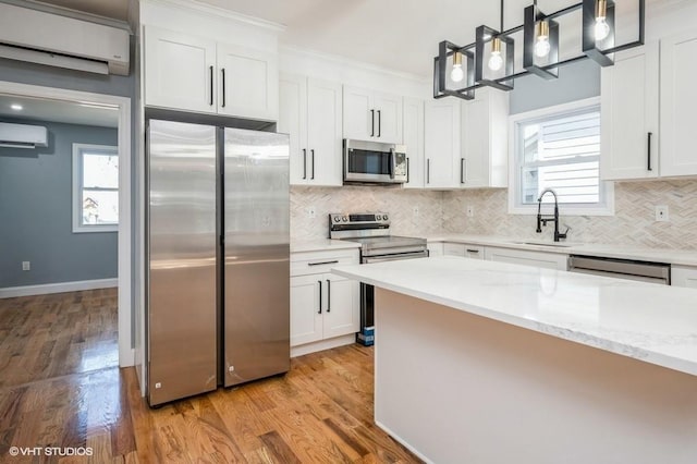 kitchen featuring stainless steel appliances, a sink, white cabinetry, light wood-style floors, and a wall mounted AC