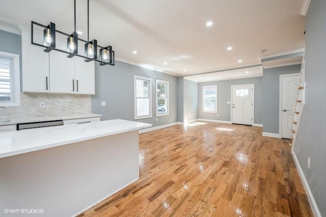 kitchen with ornamental molding, tasteful backsplash, light wood finished floors, and white cabinets