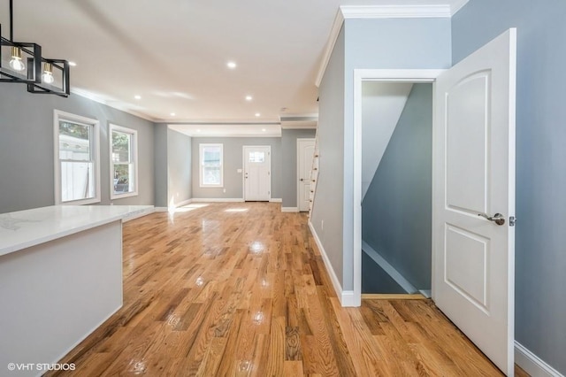 interior space featuring ornamental molding, light wood-style floors, and baseboards