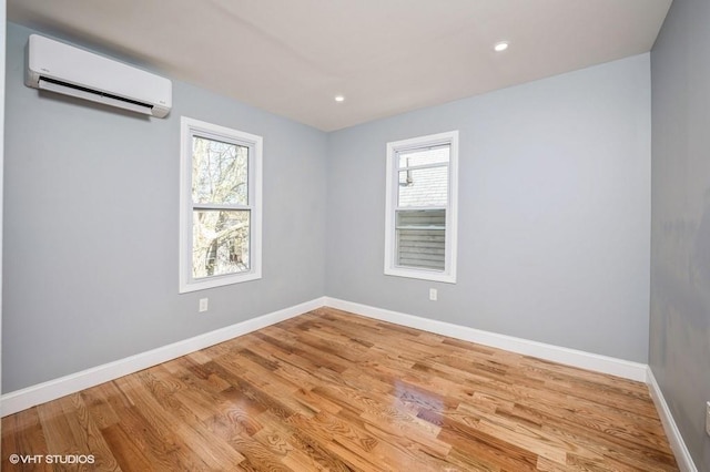 unfurnished room featuring a wall unit AC, plenty of natural light, and baseboards