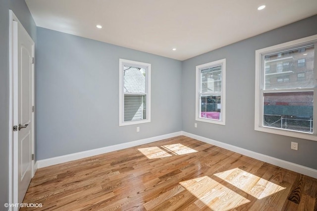 unfurnished room with recessed lighting, wood finished floors, and baseboards