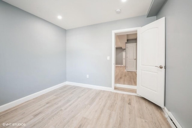 unfurnished room with a baseboard radiator, light wood-style flooring, and baseboards