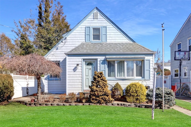 bungalow featuring a shingled roof, a front lawn, and fence