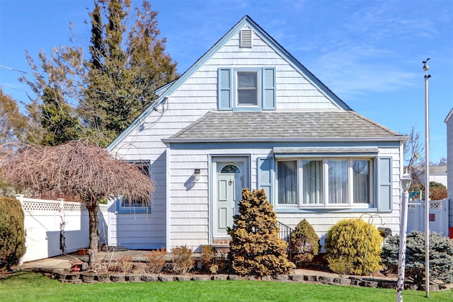 view of front of property featuring a front lawn, roof with shingles, and fence