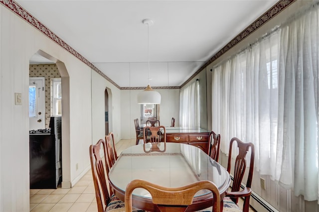 dining area featuring light tile patterned floors, a baseboard radiator, and arched walkways