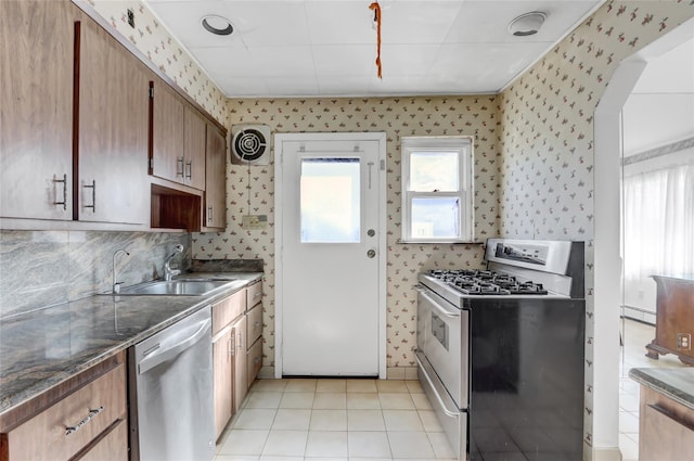 kitchen with a healthy amount of sunlight, appliances with stainless steel finishes, wallpapered walls, and a sink