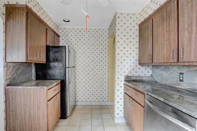 kitchen featuring wallpapered walls, light tile patterned flooring, brown cabinets, and appliances with stainless steel finishes