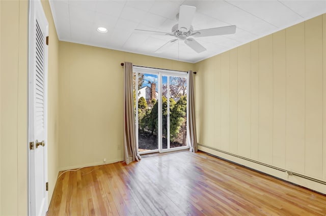 spare room featuring baseboards, a baseboard heating unit, a ceiling fan, and hardwood / wood-style flooring