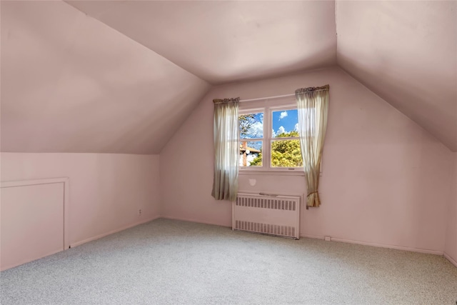 additional living space with vaulted ceiling, radiator, and carpet